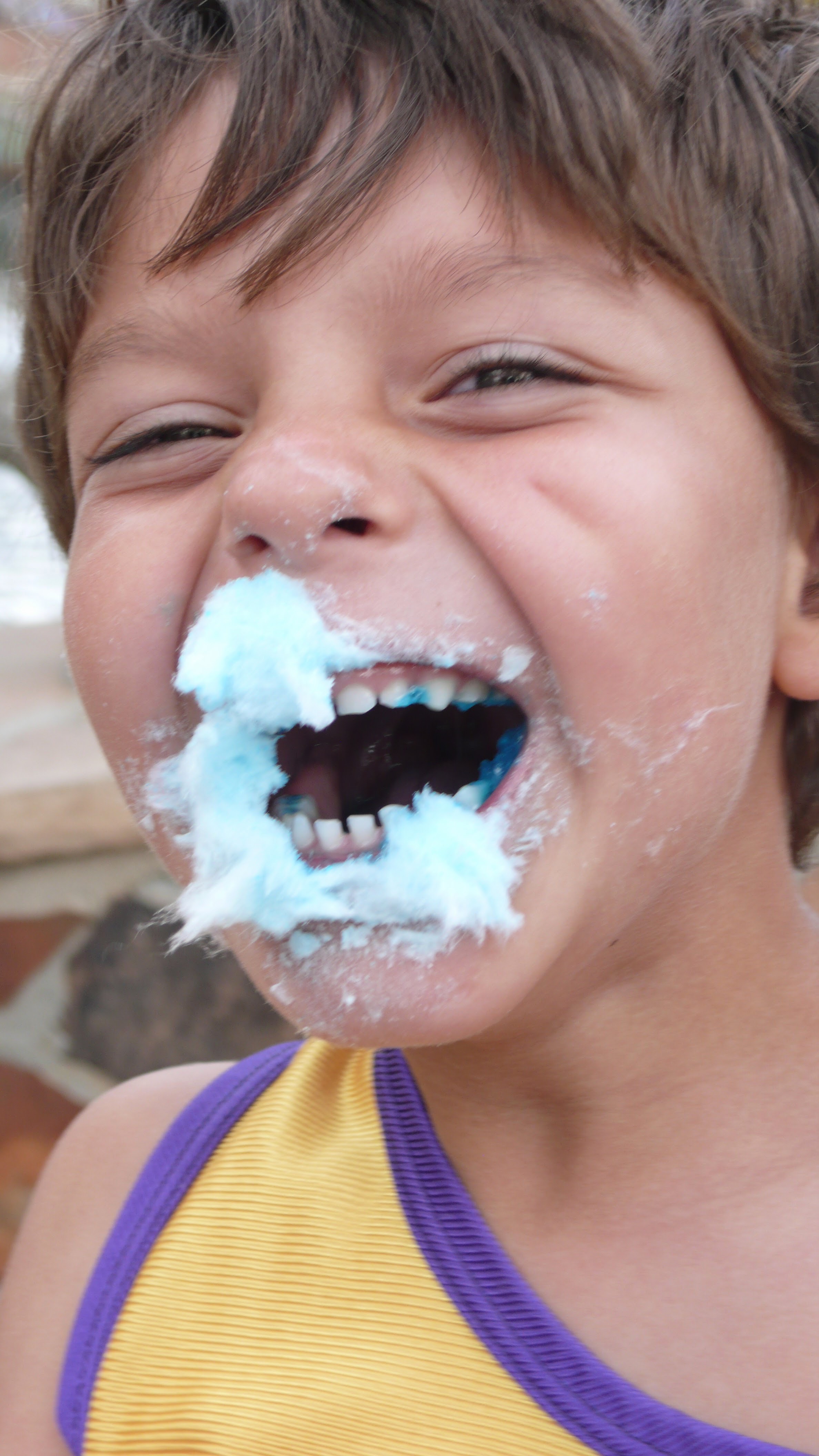 A childhood close-up of Samo laughing with blue cotton candy.