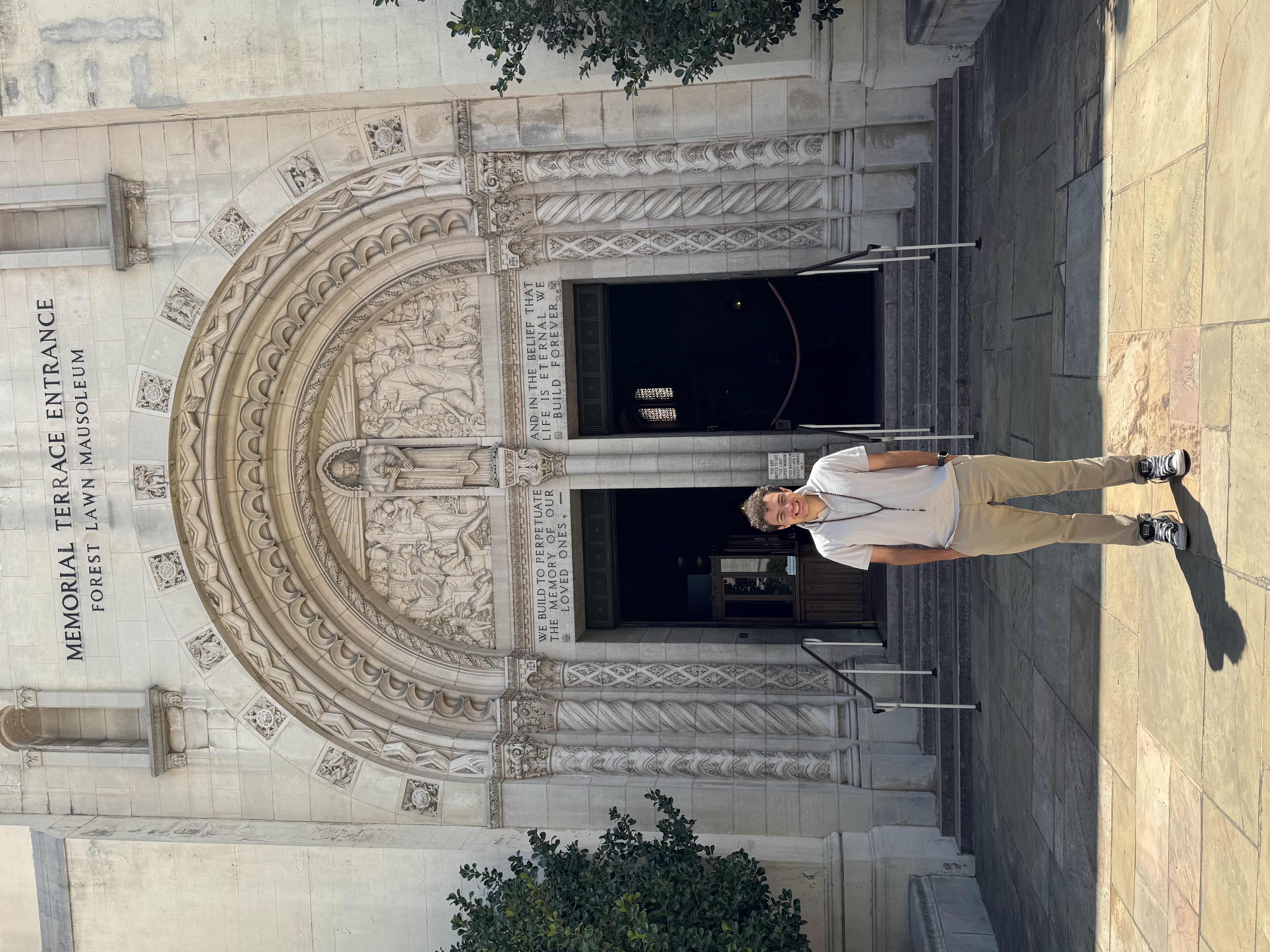 Samo standing in front of a memorial building entrance.
